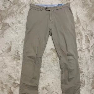 Beige chinos från Tresanti - Snygga beige chinos från Tresanti med en klassisk design. Byxorna har en midwaist passform och är tillverkade i ett bekvämt bomullsmaterial. Perfekta för en stilren look.