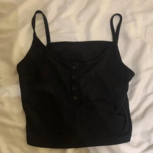 Svart ribbat linne med knappar  - Svart linne med knappar som går att knäppa och upp stänga. 