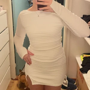 Vit långärmad klänning - Snygg vit klänning med lång ärm och en liten slits framtill. Den har en åtsittande passform och en öppen rygg som ger en elegant touch. Prislapp kvar❤️