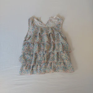 Blommig topp 💐 - Liten gullig topp, platt på baksidan!  Finns en klapp högst upp på baksidan 💕 