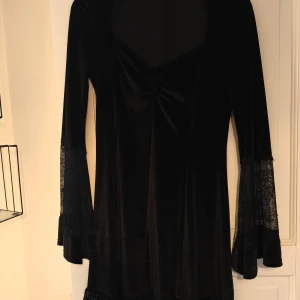 Svart långärmad klänning  - Svart klänning med spetsdetaljer Använd 1 gång Slutar strax ovanför knäna på mig (173 cm som referens) Materialet är relativt "tjockt" och typ plysch liknande.