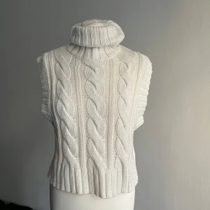 Vit stickad polotröja från Divided - Säljer en superfin vit stickad polotröja från Hm. Den är ärmlös och har ett snyggt flätmönster på framsidan. Perfekt för höst och vinter! Tröjan är i storlek XS och är i nyskick. Passar perfekt till både jeans och kjol. 🧶❄️