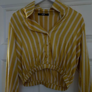 Gul och vit randig croppad skjorta från Bik Bok - Säljer en superfin gul och vit randig skjorta från Bik Bok, nyskick och skönt silkes material💛💛