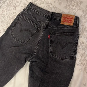 Mörkgrå jeans från Levis  - Ett par straighta mörkgråa högmidjade jeans från Levis, med fransande byxben i storlek W24, L28