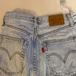 Säljer ett par Levi's Ribcage Straight Ankle jeans i storlek 27. De är ljusblåa och har en hög midja. Jeansen är i bra skick och har en klassisk femficksdesign med knappar och dragkedja. Perfekta för en avslappnad och stilren look!