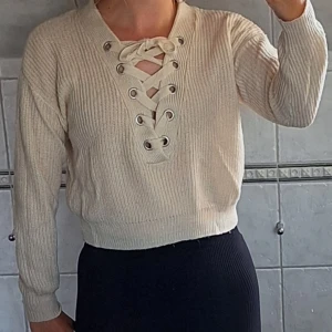 Beige stickad tröja med snörning - Säljer en superfin beige stickad tröja i storlek XS. Den har en snygg snörning framtill som ger en cool detalj. Tröjan är långärmad och perfekt för höst och vinter. Den är i fint och väldigt mysig att ha på sig. Perfekt för både vardag och fest!