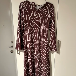 Mönstrad långklänning - Oanvänd långklänning med zebramönster i vinrött och vitt. Klänningen har långa ärmar. Från Boohoo