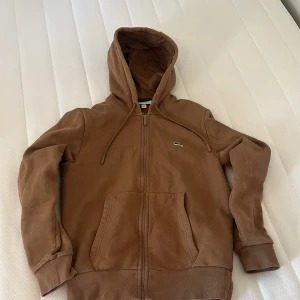 Lacoste zip - Säljer nu denna fina Lacoste hoodien. Säljer den för att den inte passar mig så bra. Den är i väldigt bra skick, inga problem alls med den.