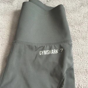Gymshark träningsbyxor  - Grå träningsbyxor från gymshark. Dem är o bra skick bara att loggan har börjat lossna som man kan se på bilderna. Det är storlek S men går att ha som M också.