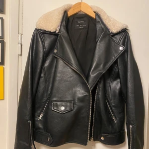 Svart skinnjacka från Bershka - Säljer en  svart skinnjacka från Bershka i storlek S. Jackan har en mysig vit fuskpäls på kragen. Buds gärna
