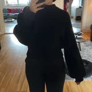 Svart stickad tröja från NA-KD - Säljer en svart stickad tröja från NA-KD i storlek M. Den har en hög krage och ballongärmar, perfekt för höst och vinter. Tröjan är i bra skick och har en loose passform som är superbekväm. Perfekt för att hålla sig varm och stilren under kyliga dagar!
