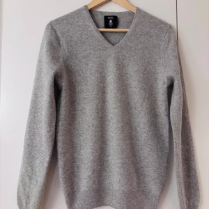 Grå kashmirtröja från Hircus - Säljer en supermjuk och lyxig grå kashmirtröja från Hircus. Den har en klassisk v-ringning och långa ärmar, perfekt för både höst och vinter. Tröjan är i mycket bra skick och är gjord av 100% kashmir, vilket gör den extra varm och skön. Perfekt för att hålla stilen när det blir kallt! 🧶