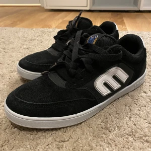 Etnies skor - Säljer ett par svarta sneakers från Etnies i bra skick. Skorna är lite chunky medans dom är gjorda i mocka och är sparsamt använda. Perfekta för skating och ger en skön streetkänsla. Skosnörerna är lite dåligt skick men det går alltid bra att byta, resten är nära jätte bra skick👍
