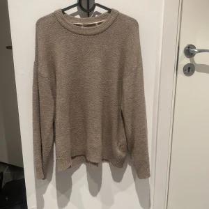 Beige stickad tröja - Mysig beige stickad tröja perfekt för kyliga dagar. Den har en avslappnad passform med långa ärmar och en rund halsringning. Perfekt för både höst och vinter, och kan enkelt matchas med jeans eller leggings för en avslappnad look.