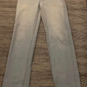 Ljusblå jeans från H&M - Säljer ett par ljusblå jeans från H&M:s 'The Water Saving Collection'. De har en straight passform i 90-talsstil och är perfekta för en avslappnad look. Jeansen har en klassisk design med knappar och dragkedja framtill.