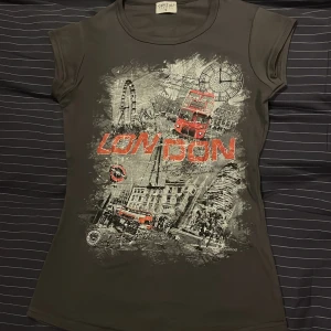 Grå topp - En fin grå t-shirt med London-motiv i rött och grått. Köpt i London 2023 men har inte kommit till användning! Priset går att diskutera 💕