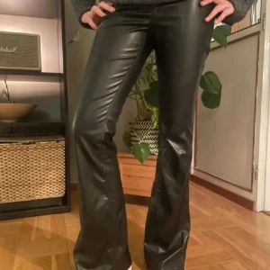 Svarta skinnbyxor - Säljer ett par snygga svarta skinnbyxor i bootcut-stil. De är perfekta för en kväll ute eller en cool vardagslook. Passar perfekt till höst- och vintergarderoben!🥰 De är högmidjade men de tänker man inte på!😍