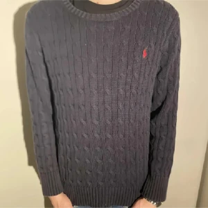 Mörkblå stickad tröja från Ralph Lauren - Säljer en snygg mörkblå stickad tröja från Ralph Lauren med det klassiska röda logotypen på bröstet. Tröjan har en rund hals och långa ärmar, perfekt för kyliga dagar. Den är i mycket bra skick och passar både till vardags och lite finare tillfällen.