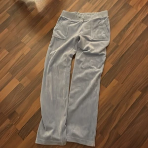 Ljusblå mjukisbyxor från Juicy Couture - Säljer ett par superbekväma ljusblå mjukisbyxor från Juicy Couture i storlek M. Byxorna har en loose passform och är gjorda i mjuk velour, perfekt för mysiga dagar hemma. De har en elastisk midja och praktiska fickor fram. Perfekta för både chill och stil! 💙