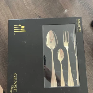Bestickset Baguette Champagne 24 delar - Säljer ett elegant bestickset från Gense, modell Baguette i färgen Champagne. Setet innehåller 24 delar och har en stilren design med en lyxig finish. Perfekt för både vardag och festliga tillfällen. Besticken ligger i en snygg svart förpackning.