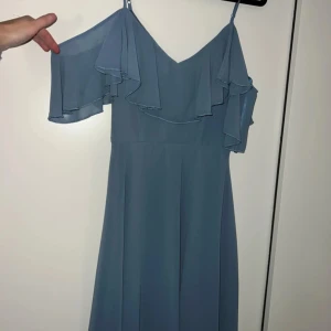 Blå klänning från Sisters Point - Säljer en superfin blå klänning från Sisters Point (Lyckliga jag)  i storlek XS. Den har en offshoulder-design med volangdetaljer och är perfekt för sommarens fester. Klänningen är i mycket bra skick och har en dragkedja i ryggen för enkel påklädning. Perfekt för en somrig look! 💙