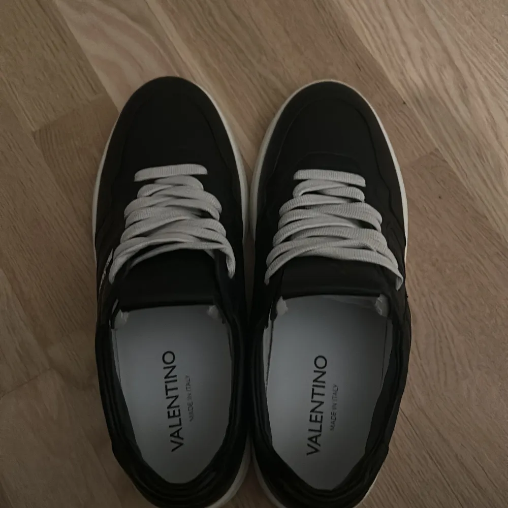 Säljer ett par snygga svarta Valentino sneakers i skinn med vita snören och sula. Helt oanvända kvitto finns. De har en stilren design. Perfekta för både vardag och vintern nu🖤. Skor.