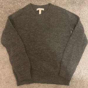 Grå stickad tröja från H&M - Mysig grå stickad tröja från H&M i storlek XS. Tröjan har en klassisk design med rund hals och långa ärmar. Passar både till vardags och mer avslappnade tillfällen. Inga defekter.