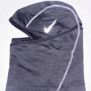 Svart Nike balaclava med reflexer - Snygg och funktionell balaclava från Nike, perfekt för träning i kallt väder. Den är tillverkad i ett mjukt och stretchigt material med reflex sömmar och en reflekterande Nike-logga. Passar bra under hjälm eller mössa för extra värme.