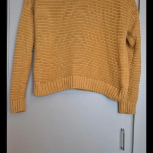 Gul stickad tröja från Divided - Säljer en superfin gul stickad tröja från Divided. Den är perfekt för höst och vår med sin mysiga och varma känsla. Tröjan har en normal passform och långa ärmar, vilket gör den idealisk för kyligare dagar. Ribbstickade muddar vid ärmslut och nederkant ger en snygg finish. Passar perfekt till jeans eller kjol!