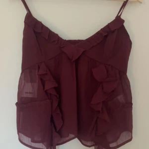 Vinröd linnetopp från Bik Bok - Snygg vinröd linnetopp från Bik Bok i storlek S. Toppen har smala axelband och fina volangdetaljer framtill. Perfekt för sommardagar eller en festlig kväll. Materialet är lätt och luftigt, vilket gör den bekväm att bära.