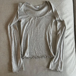 Grå ribbad topp från Bubbleroom - Super gullig tröja med fina muddar och nederkant. Den är även fint sydd i kragen och har ett mönster på skövla tröjan. Bekväm! Sen har extra långa armar. Helt oanvänd!