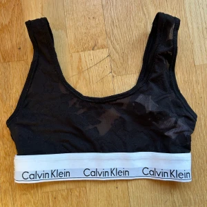 Svart bralette från Calvin Klein - Säljer en snygg svart bralette från Calvin Klein i storlek XS. Den har en elastisk vit kant med Calvin Klein-loggan och är tillverkad i ett mjukt och bekvämt material. Perfekt för vardagsbruk eller under en lös topp. 🖤 aldrig använd 