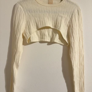 Beige ribbad croppad tröja - Säljer en superfin beige croppad tröja från H&M. Den är ribbad och har långa ärmar, perfekt för lager på lager-stil. Tröjan är i bra skick och passar perfekt till både vardag och fest. Skicka ett meddelande vid intresse!