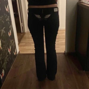 Svarta jeans från Robin's Jean - Snygga svarta jeans från Robin's Jean med coola broderade vingar på bakfickorna. De har en låg midja och en bootcut-stil som ger en retro vibe. Perfekta för både vardag och fest! 🖤midjemått tvärs över 39cm. Innerbenslängd 80cm.
