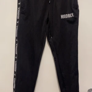 Svarta mjukisbyxor från Hoodrich - Säljer ett par svarta mjukisbyxor från Hoodrich i storlek M. Byxorna har en snygg logga längs sidorna och en dragkedja framtill. För en avslappnad stil eller träning. De är i mycket bra skick och superbekväma!