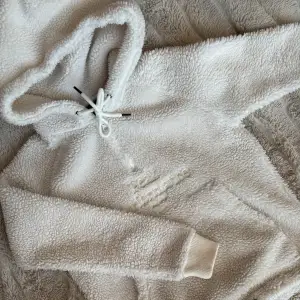 Mysig vit fleece hoodie perfekt för kalla dagar. Den har en stor ficka fram och justerbar dragsko i huvan. Supermjuk och varm, idealisk för både hemmamys och utomhusaktiviteter. Passar perfekt till höst och vinter!