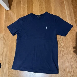 Ralph Lauren T-Shirt - Tja, säljer en Raffe T-shirt som är mörkblå. Skick 9/10. Inte mycket tecken på användning. Passar dig som är mellan 160-165. Storlek xxs. 