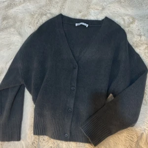 Mörkgrå kofta från zara - Säljer en mysig mörkgrå kofta från zara i bra skick. Den har en v-ringad design med knappar framtill och långa ärmar. Perfekt för höst och vinter, och den är superlätt att matcha med andra plagg. Perfekt för lager-på-lager-stil!