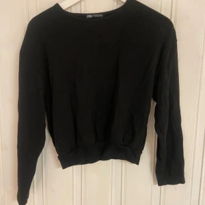 Svart tröja från Zara - Säljer en stilren svart tröja från Zara. Perfekt för både vardag och fest. Tröjan har en normal passform och långa ärmar, vilket gör den idealisk för höst och vinter. Materialet känns mjukt och bekvämt. Ett måste i garderoben för den som gillar enkel och tidlös stil.