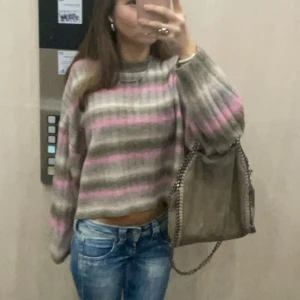 Randig stickad tröja i grått och rosa - Superfin stickad tröja med randigt mönster i grått och rosa. Den är croppad och har långa armar