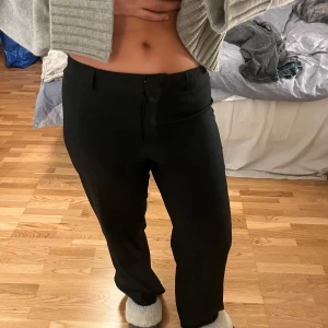 Svarta kostymbyxor  - Säljer ett par svarta kostymbyxor i mycket bra skick. De har en normal passform och är perfekta för både vardag och fest. Byxorna har en klassisk design med knapp och dragkedja framtill. Står inget märke eller storlek i de men skulle tro att det är S/M