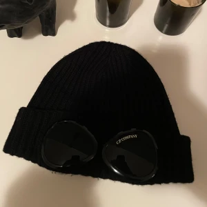 Svart mössa från C.P. Company - Snygg svart mössa från C.P. Company, skicket på mössan är 10/10. Köpte den i slutet av förra vintern. Typ aldrig använd.