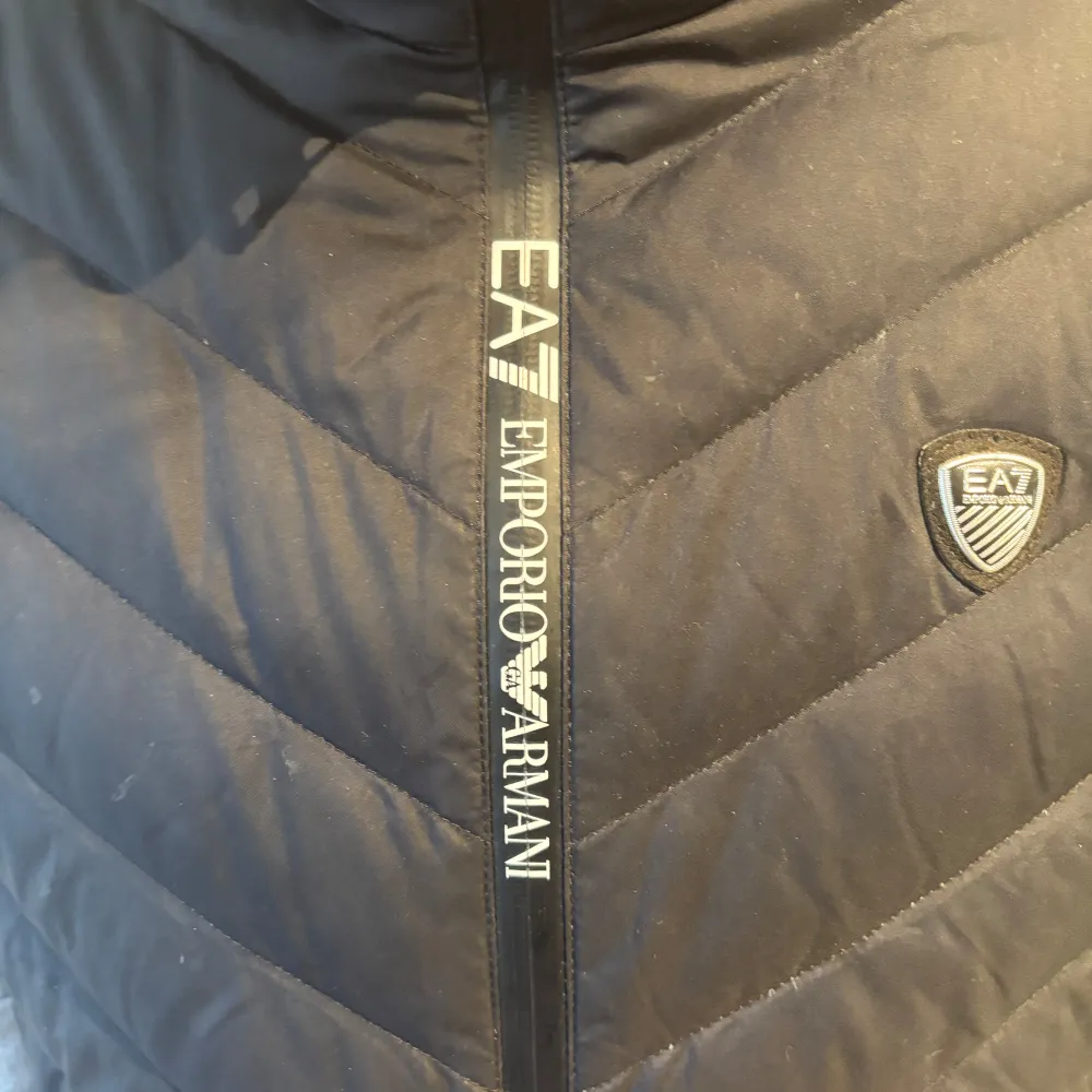 Säljer en snygg svart quiltad väst från Emporio Armani. Den har en dragkedja framtill och ett stilrent märke på bröstet. Perfekt för lager-på-lager under höst och vår. Passar både till vardags och lite finare tillfällen. Jag säljer den då den är lite stor för mig.. Jackor.