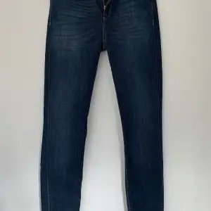 Säljer ett par snygga mörkblå jeans från Selected Femme i modellen Sfelena Mid Rise. De är ej använda och i ny skick och har en klassisk design med fem fickor och knappgylf. Perfekta för både vardag och fest!