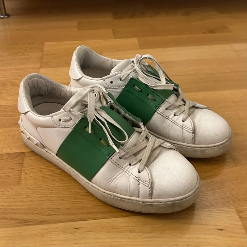 Valentino-sneakers i vitt skinn med gröna detaljer. Använt skick men inga defekter bortsett från en nit på ena skon där spetsen delvis ”trubbats av”. Storlek 40, något stora i storleken. Ursprungligen köpta på Vestiaire Collective så självklart äkta, kan skicka bild på orderbekräftelsen. Lågt pris då inga tillbehör följer med pga jag fick själv inga sådana vid originalköpet 💚. Skor.