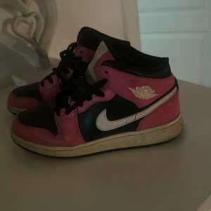 Nike Air Jordans i svart och rosa - Säljer ett par coola Nike Air Jordans i svart och rosa. De har en klassisk design med snörning och en vit sula. Perfekta för både vardag och fest! Skorna är i bra skick med lite slitage på sulan.