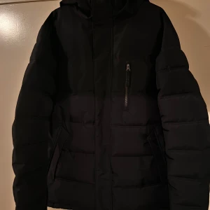 Svart pufferjacka från Take Off - Säljer en svart pufferjacka från Take Off i storlek S. Jackan har en dragkedja framtill och en praktisk ficka med dragkedja på bröstet. Perfekt för kalla dagar med sin vadderade design. Passar både höst och vinter. 🖤