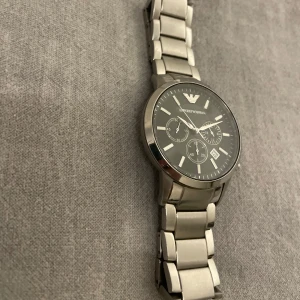 Emporio Armani silver klocka - Säljer min fina rostfria silver Armani klocka, nypris ca 4000kr. Klockan är 43mm i storlek, vattentät upptill 50m under vatten, har en bra vikt till sig och är väldigt ståtlig och tålig. Riktigt väl omhändertagen och i fint skick utan några repor överhuvudtaget.