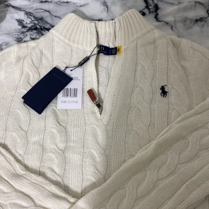 Vit stickad tröja från Ralph Lauren - Säljer en superfin vit stickad tröja från Ralph Lauren. Den har en dragkedja framtill och det klassiska logotypbroderiet på bröstet. Perfekt för kyliga dagar med sin mysiga och stilrena design. Passar både till vardags och lite finare tillfällen. 