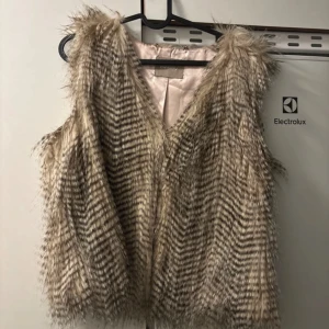 Beige pälsväst från Orsay - Säljer en superfin beige pälsväst från Orsay. Den är perfekt för att ge din outfit en extra touch av stil. Västen är i mycket bra skick och har en mjuk och fluffig känsla. Passar perfekt för höst och vinter. Storleken är inte angiven, men den ser ut att ha en normal passform.